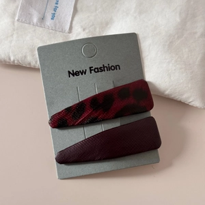 Detail of leopard print leather and dark red snap hair clips on a gift card display
