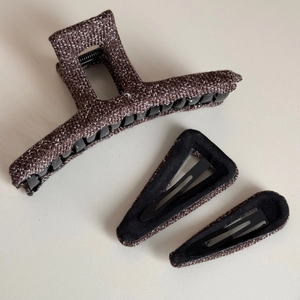 Detail view of dark brown knit texture hair claw clip and black triangular metal hairpins