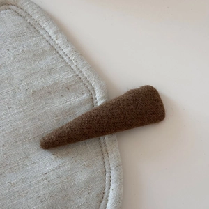 Detail view of dark brown wool felt headband with textured fabric on linen
