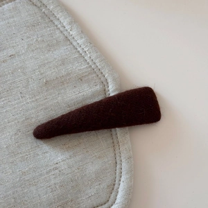 Macro shot of dark brown felt fabric texture on a minimalist triangular hair clip
