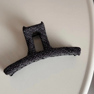 Close-up of a large grey tweed fabric hair claw clip with minimalist metal spring design