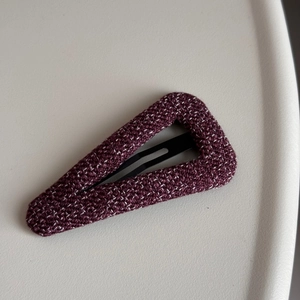 Close-up of a triangular snap hair clip covered in premium purple tweed fabric with white spots
