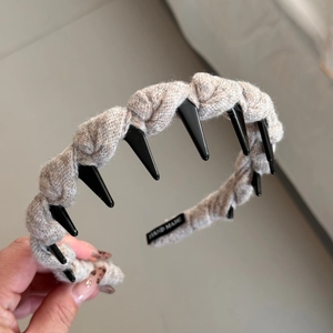 Détail d'un serre-tête gris tricoté à la main avec de longues dents et étiquette tissée