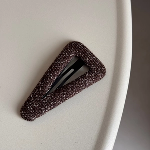 Close-up of deep brown fabric hair clip with white dots and refined woven texture