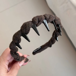 Détail d'un serre-tête tressé marron fait main avec pointes punk noires et texture