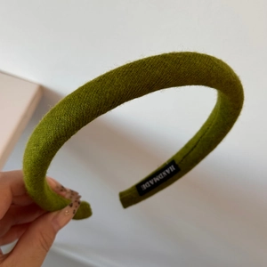 Detail of green handmade knitted sponge headband with woven texture and tag