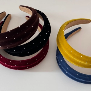 Detail view of five velvet padded headbands with sparkling rhinestones in various colors