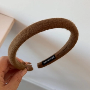 Close-up of handmade dark brown woolen headband featuring a woven HANDMADE textile label