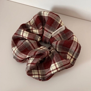 Detailed close-up of brown plaid scrunchie with handmade woven label on fabric