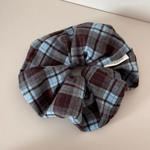 Close-up of blue and brown plaid fabric scrunchie with a handmade woven label