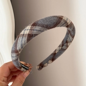 Detailed close-up of brown plaid fabric headband with a handmade label inside