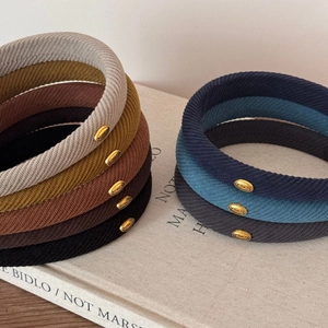 Detail of Korean style twill headbands showing oval gold metal tags and eight color options