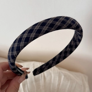 Detail of grey plaid thick fabric headband showing handmade logo and non-slip inner teeth