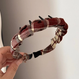 Detail of a brown plaid headband with integrated black hair clips for styling and braiding