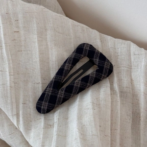 Detail of dark plaid fabric pattern on a triangular geometric hair clip accessory