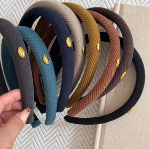 Close-up of twill fabric headbands with oval gold metal tags and handmade labels