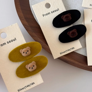 Detailed view of plush bear hair clips in yellow and black on display card