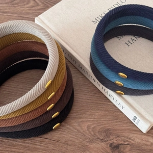 Close-up of corduroy texture and circular gold logo detail on high crown headbands