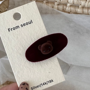 Detail of cute brown flocked bear on a dark red velvet oval hair clip for styling