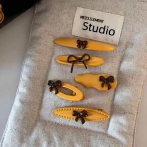 Detailed macro view of 5-piece yellow hair clip set with brown resin bow accents