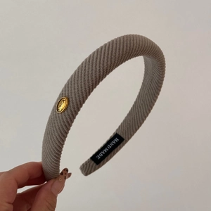 Detail of grey knitted padded headband with gold metal tag and handmade label