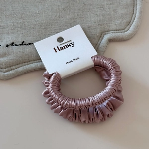 Close-up of pink satin hair scrunchie with silky texture on a handmade display card