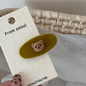Detail of a mustard yellow velvet oval hair clip featuring a cute 3D flocked brown bear
