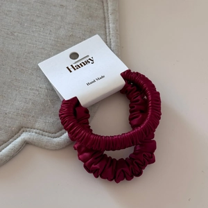 Detail of dark red satin scrunchies set with silky texture on a handmade display card