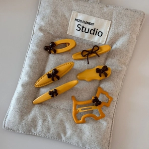 Set of 6 yellow matte hair clips with brown bows and dog shape on grey fabric