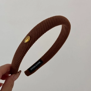 Macro detail of brown knitted headband showing twill texture and gold Korea emblem