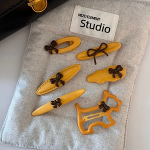 Detail view of 6-piece yellow hair clip set with brown bows on linen fabric background