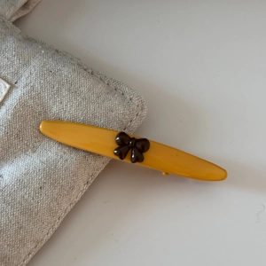 Detail of yellow duckbill hair clip with brown bow on minimalist canvas bag edge