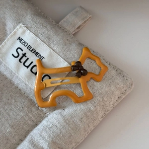 Close-up of yellow terrier dog hair clip with brown bow on premium canvas bag background