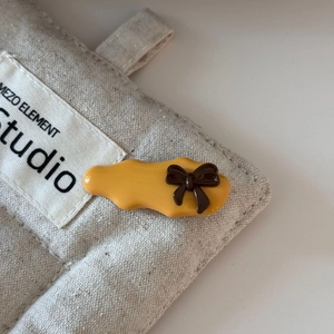Macro shot of yellow resin hair clip with a dark brown bow on linen fabric texture