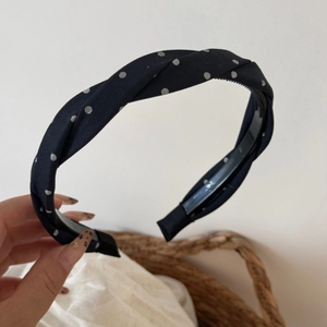 Detail of navy blue polka dot twisted headband with non-slip inner teeth and soft texture