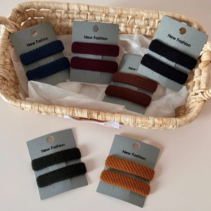 Set of two ribbed fabric elastic hair scrunchies on a grey display card with twill texture