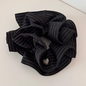 Detail of black striped hair scrunchie with a silver heart-shaped metal pendant charm