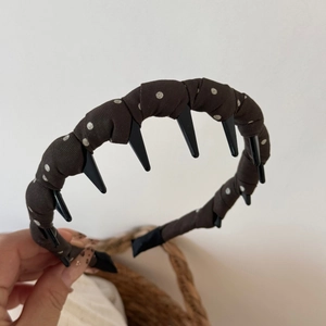 Detail showing non-slip plastic teeth inside dark coffee polka dot fabric headband