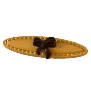Yellow vintage bow hair clip with embossed polka dots on a white background