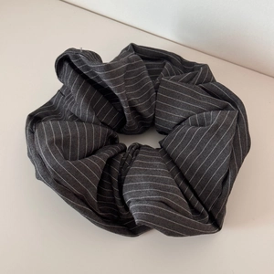 Close-up of dark grey striped fabric scrunchie showing detailed texture and pleated design