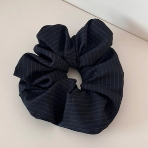 Close-up of black striped fabric scrunchie with detailed texture and elastic structure