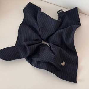 Detailed view of navy blue striped fabric hair tie with handmade label and silver heart charm
