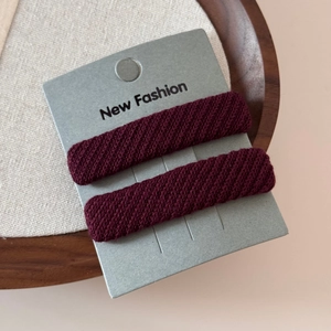 Close-up of burgundy twill fabric sponge hair clips on a decorative wooden display