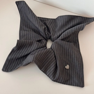 Detail of grey striped scrunchie fabric with a small heart-shaped metal pendant