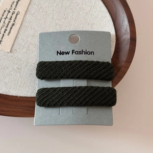 Detail of dark green twill fabric sponge hair clips showing textured knit pattern