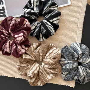 Détail de quatre chouchous en tricot bordeaux et à rayures sur un tapis beige