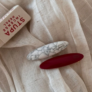 Detail of vintage marble white and burgundy acetate hair clips on linen fabric backdrop