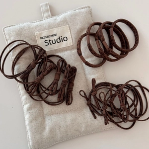 Detailed view of leopard print hair ties and a bow scrunchie with a branded storage pouch