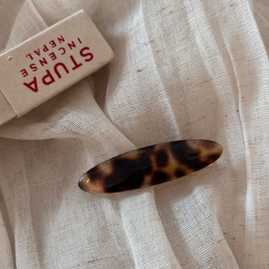 Macro shot of vintage tortoiseshell acetate oval hair clip on a natural linen surface