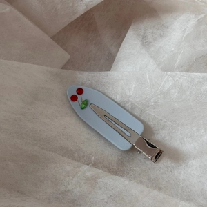 Detail of blue acetate hair clip featuring a sparkling red rhinestone cherry and leaf